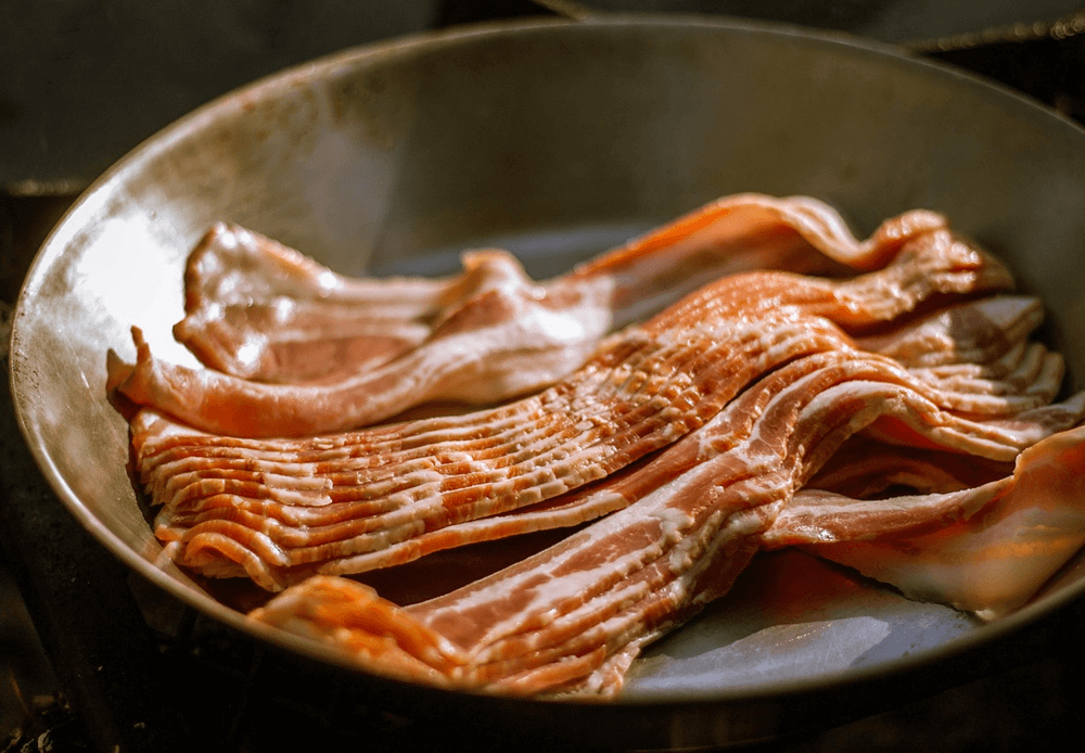 Raw smoked streaky bacon strips in a skillet, ready to be pan-fried